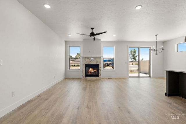 1700 Black Elm, Star, ID 83669 - unfurnished living room with a high end fireplace, light wood-style floors, a chandelier, a textured ceiling, and recessed lighting