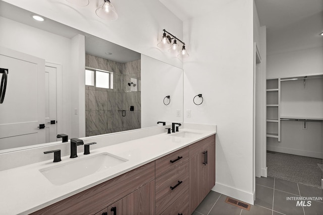 bathroom featuring baseboards, tile patterned floors, a shower stall, and a sink