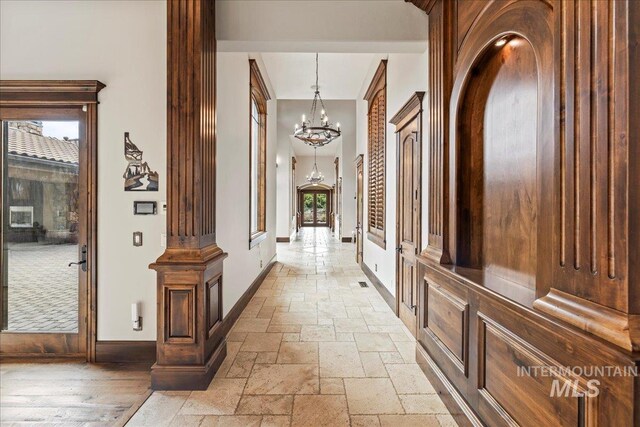 7600 W Ledgerwood Ln, Meridian, ID 83646 - hallway featuring an inviting chandelier, a healthy amount of sunlight, baseboards, and stone tile flooring