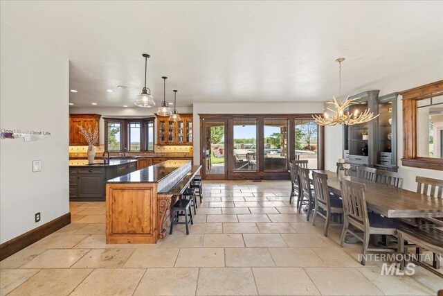 7600 W Ledgerwood Ln, Meridian, ID 83646 - kitchen featuring a chandelier, a kitchen bar, a kitchen island, baseboards, and dark countertops