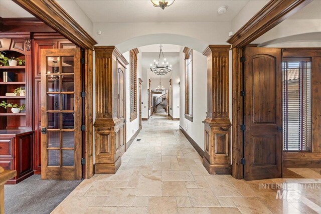 7600 W Ledgerwood Ln, Meridian, ID 83646 - hall featuring stone tile floors, decorative columns, baseboards, arched walkways, and french doors