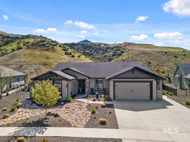 ranch-style house featuring a garage, fence, a mountain view, and concrete driveway