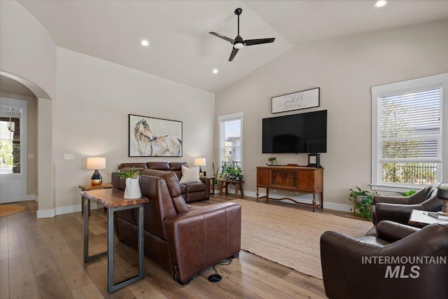 living room with a ceiling fan, arched walkways, a wealth of natural light, and lofted ceiling