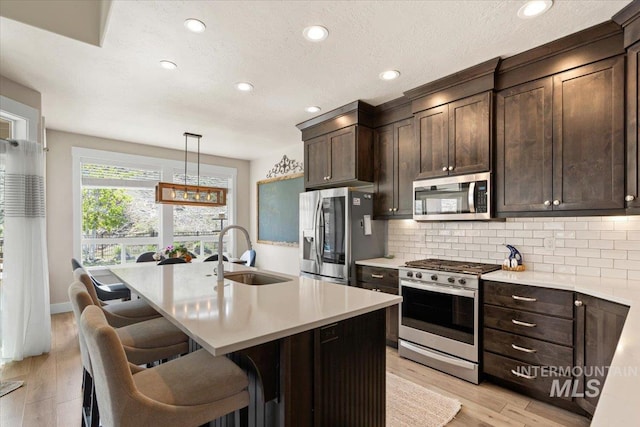 kitchen with a sink, appliances with stainless steel finishes, tasteful backsplash, and light countertops