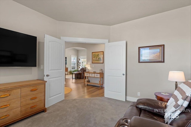 living room with arched walkways and light colored carpet