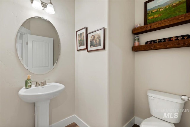 half bathroom with toilet and baseboards