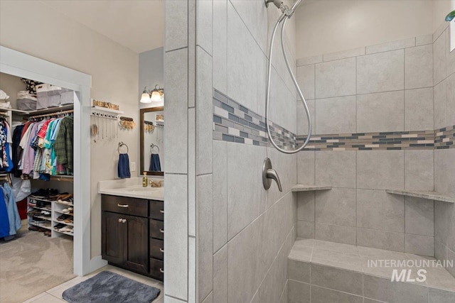 full bathroom featuring vanity, tiled shower, and a spacious closet