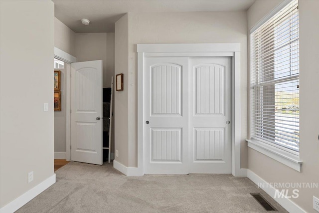 unfurnished bedroom featuring baseboards, visible vents, light carpet, and a closet
