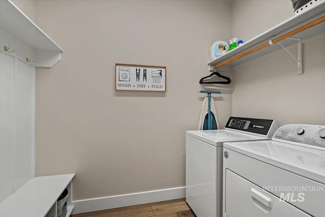 washroom featuring baseboards, laundry area, washer and clothes dryer, and light wood-type flooring