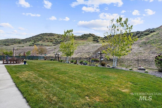 view of community featuring a lawn, a mountain view, and fence