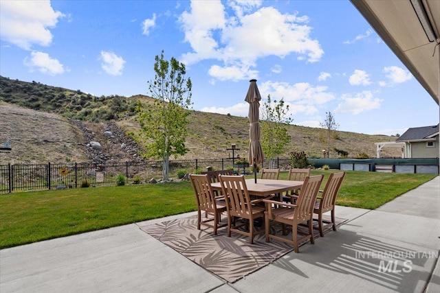 view of patio / terrace with outdoor dining area, a mountain view, and fence