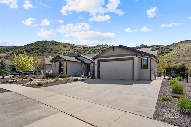 ranch-style house featuring concrete driveway, fence, a mountain view, and a garage