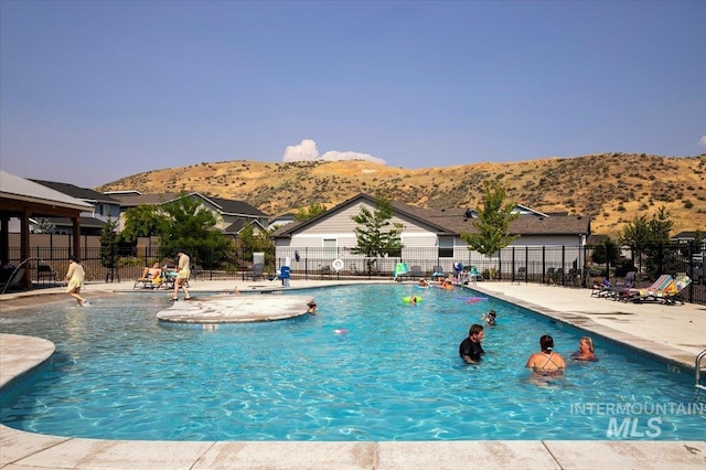 community pool featuring fence, a mountain view, and a patio area
