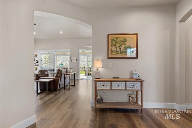 hall with arched walkways, baseboards, recessed lighting, and wood finished floors