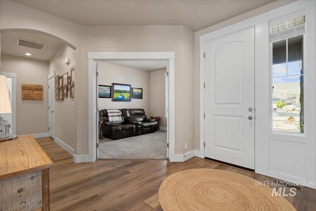 entryway with arched walkways, recessed lighting, baseboards, wood finished floors, and visible vents