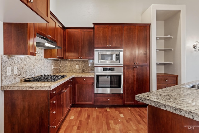 1148 E Winding Creek Dr, Eagle, ID 83616 - kitchen with stainless steel appliances, under cabinet range hood, light wood-type flooring, tasteful backsplash, and light countertops