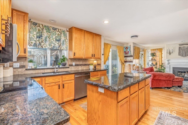 kitchen with light wood finished floors, open floor plan, appliances with stainless steel finishes, and a sink