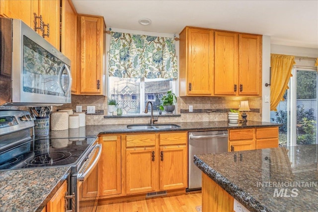 kitchen with visible vents, dark stone countertops, appliances with stainless steel finishes, and a sink