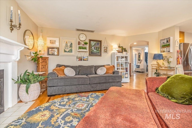 living room featuring light wood-style flooring, visible vents, and arched walkways