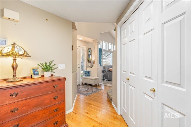 corridor with lofted ceiling, decorative columns, light wood-style floors, and baseboards