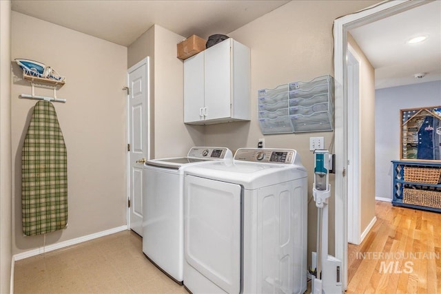 laundry room with washing machine and clothes dryer, cabinet space, light wood finished floors, and baseboards