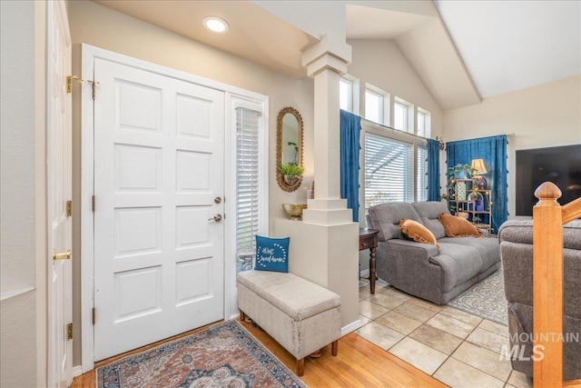 entrance foyer with ornate columns, wood finished floors, and vaulted ceiling