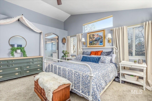 bedroom featuring high vaulted ceiling, a ceiling fan, ensuite bath, arched walkways, and carpet flooring