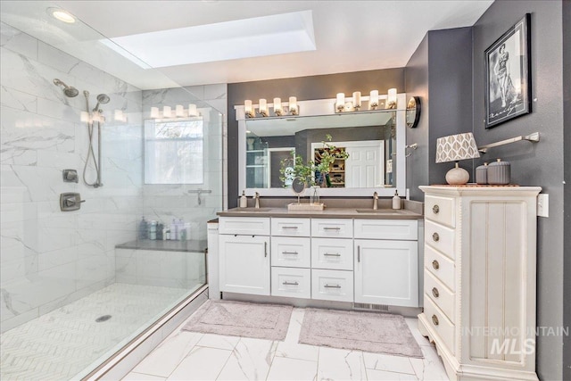 bathroom featuring double vanity, marble finish floor, a tile shower, and a sink