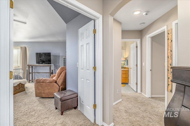 hallway with arched walkways, baseboards, and carpet