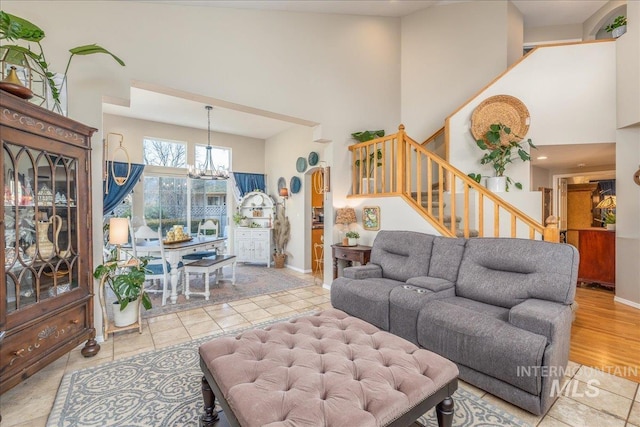 living area with stairway, baseboards, a high ceiling, and an inviting chandelier