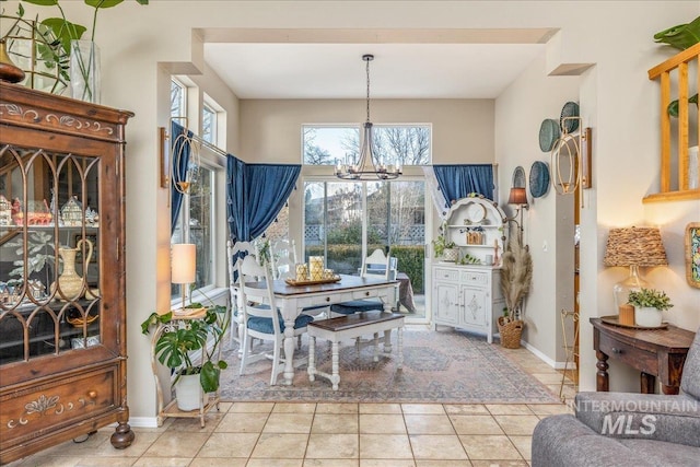 tiled dining area with a notable chandelier and baseboards