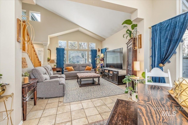 living area with stairs, plenty of natural light, light tile patterned floors, and high vaulted ceiling