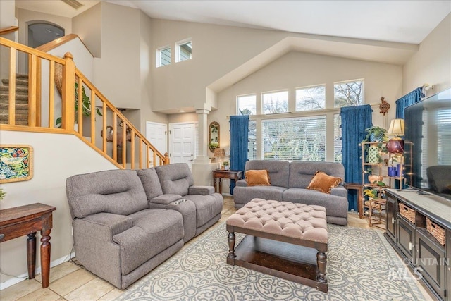 living room with stairs, light tile patterned flooring, ornate columns, and high vaulted ceiling