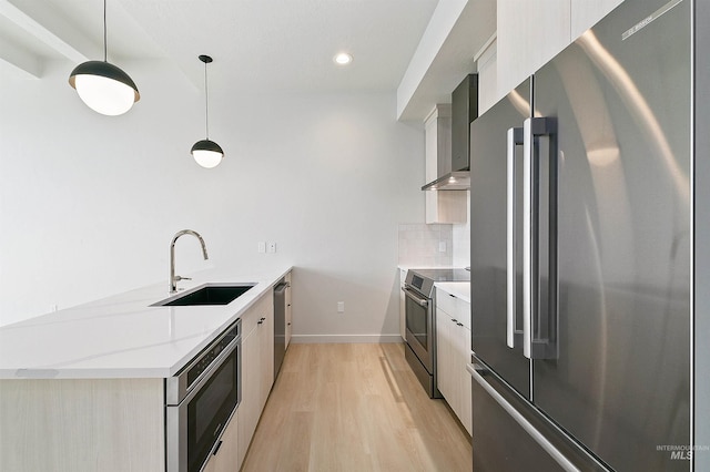 kitchen with a sink, stainless steel appliances, wall chimney range hood, modern cabinets, and tasteful backsplash