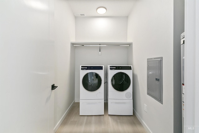 laundry room with visible vents, washing machine and clothes dryer, laundry area, electric panel, and light wood-type flooring