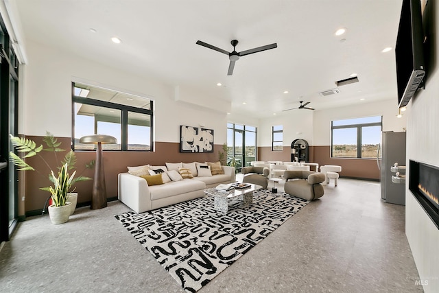 living area with a glass covered fireplace, recessed lighting, a ceiling fan, and visible vents