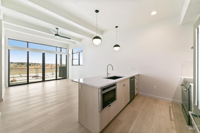 kitchen featuring a sink, a peninsula, stainless steel appliances, a ceiling fan, and modern cabinets