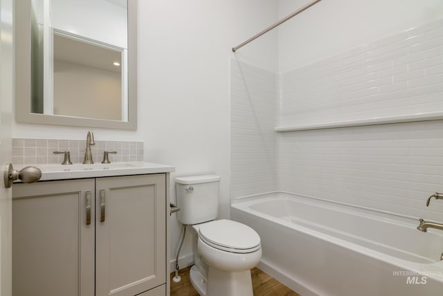 full bathroom featuring wood-type flooring, backsplash, vanity, toilet, and washtub / shower combination