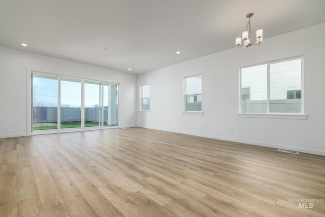 spare room with an inviting chandelier and light hardwood / wood-style flooring