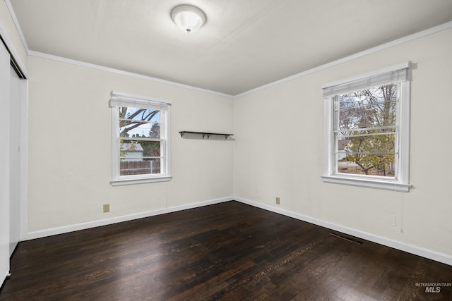 spare room with ornamental molding, plenty of natural light, and dark wood-type flooring