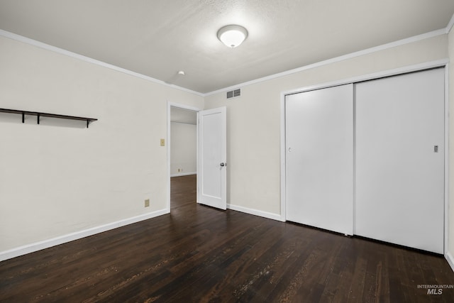 unfurnished bedroom featuring a textured ceiling, dark hardwood / wood-style floors, crown molding, and a closet