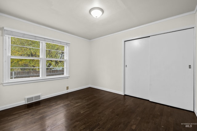 unfurnished bedroom with dark hardwood / wood-style floors, ornamental molding, and a closet