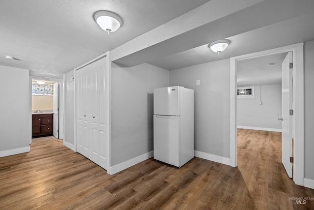 kitchen featuring wood-type flooring, white fridge, and dark brown cabinets