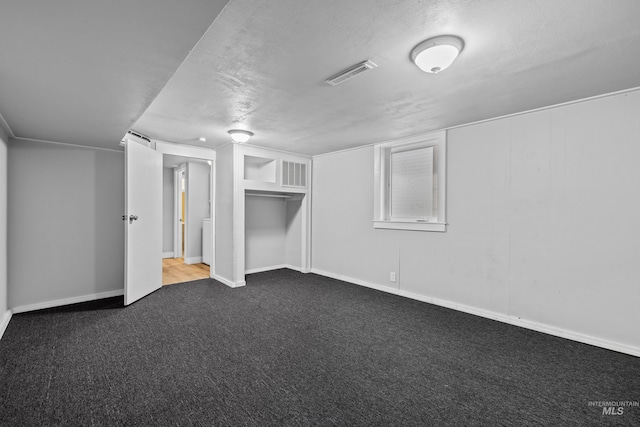 additional living space featuring dark colored carpet and a textured ceiling