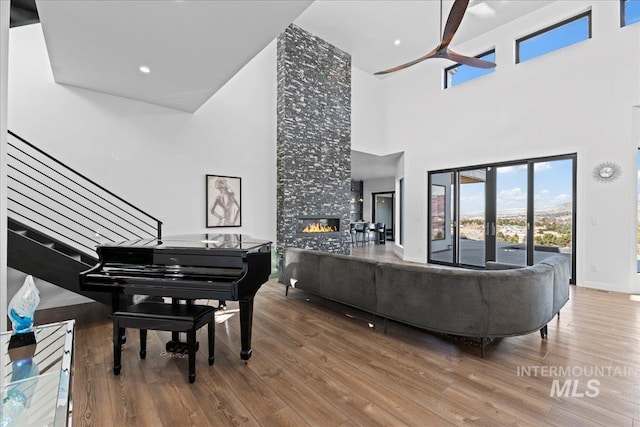 3492 E Heartleaf Dr, Boise, ID 83716 - living room featuring a tiled fireplace, wood finished floors, a towering ceiling, baseboards, and ceiling fan
