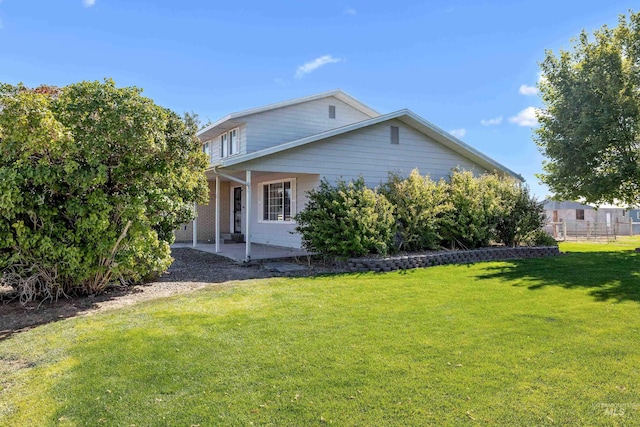 view of side of property featuring a lawn and a patio