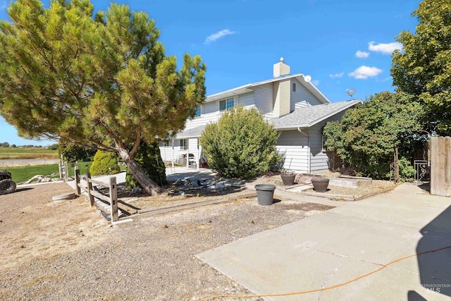 view of property hidden behind natural elements with a patio and an outdoor fire pit