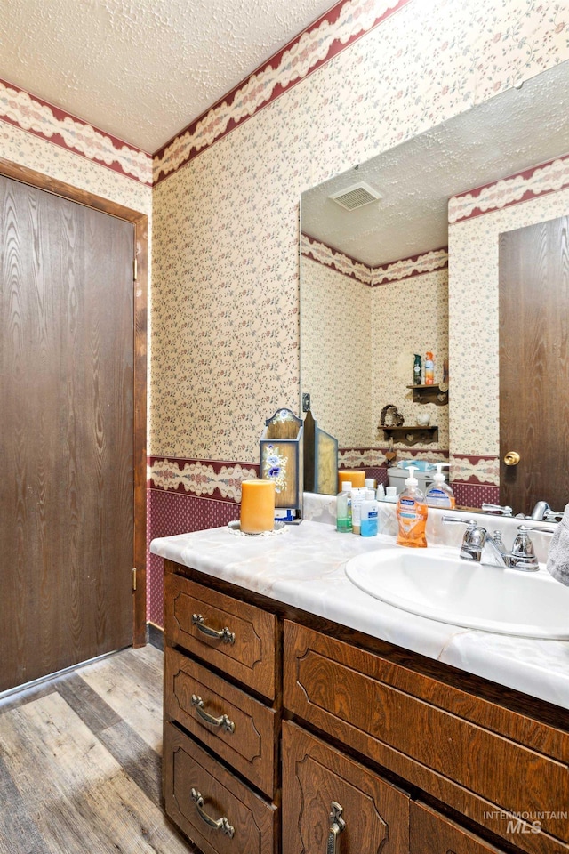 bathroom with wood-type flooring, vanity, and a textured ceiling