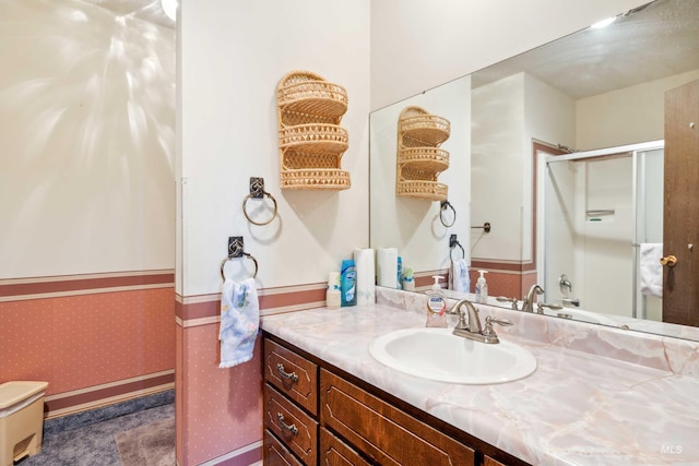 bathroom featuring a shower with door and vanity