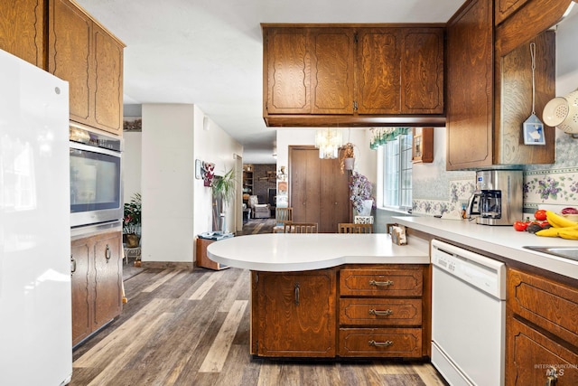 kitchen featuring kitchen peninsula, dark hardwood / wood-style flooring, and white appliances